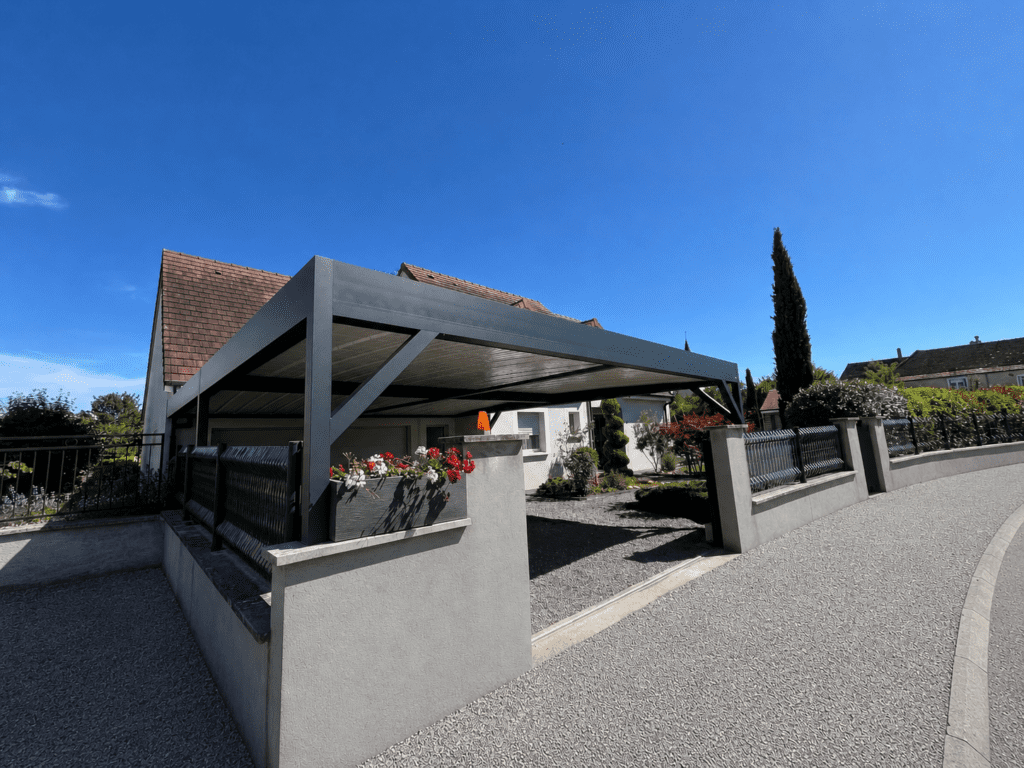 Carport en aluminium fixé sur murets à l'intérieur d'une cour