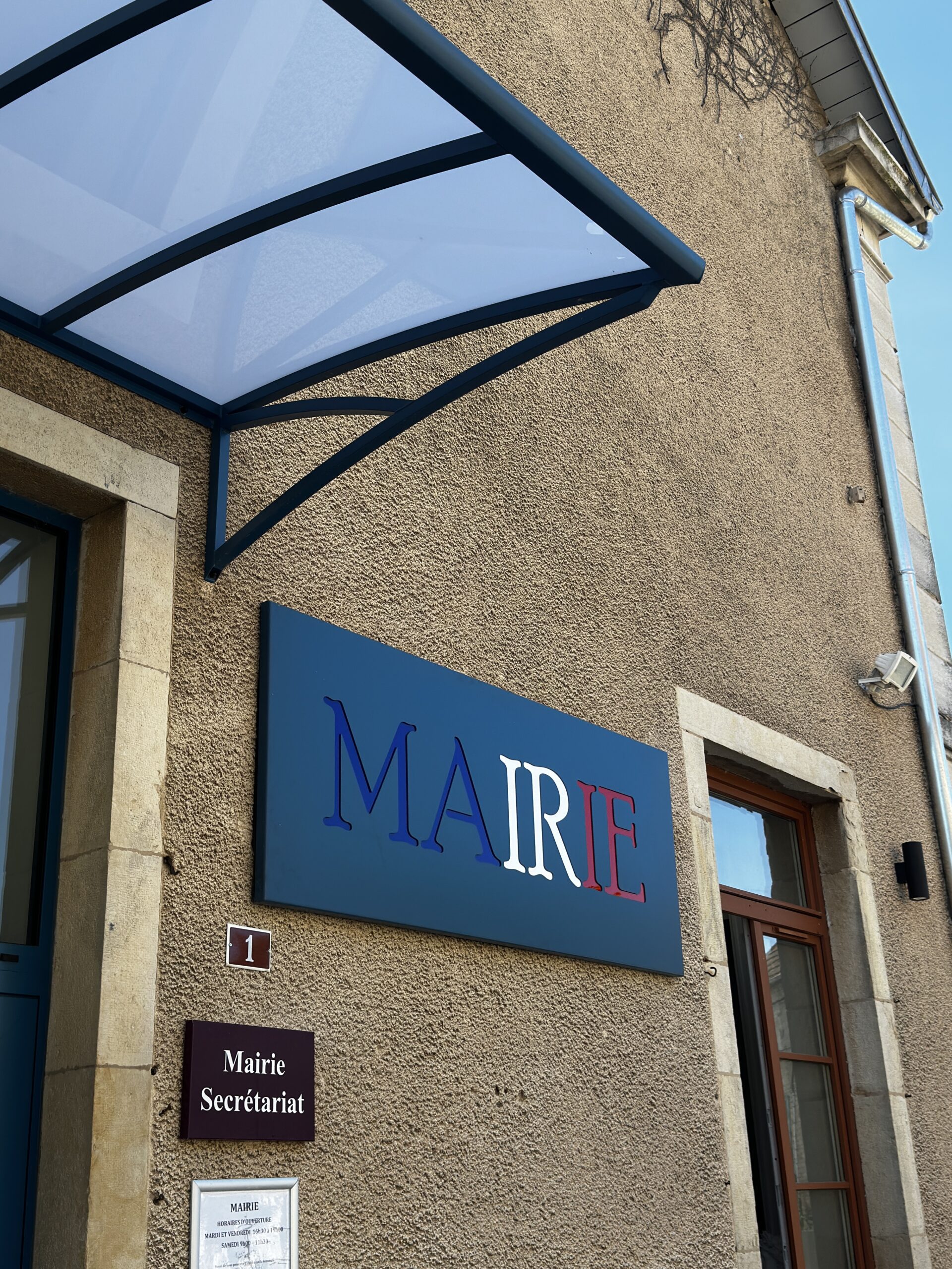 Enseigne de mairie en aluminium bleu, blanc et rouge installée sous une marquise en aluminium thermolaqué bleu.