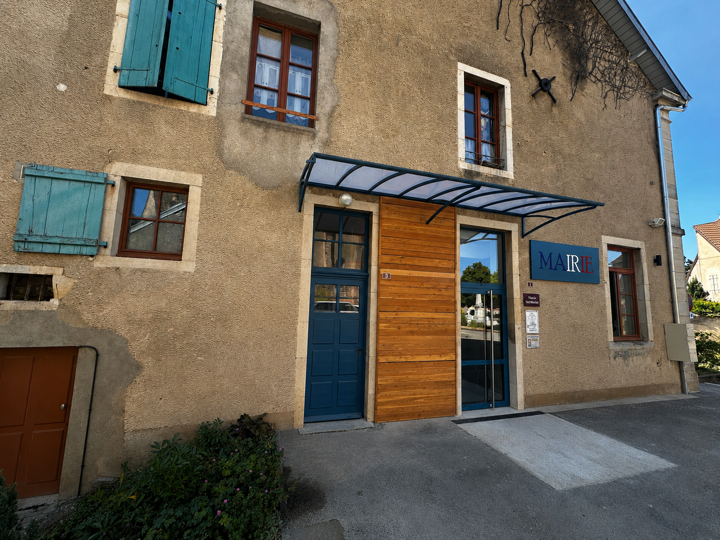 Vue de face d'une marquise en aluminium thermolaqué bleu installée sur la façade d'une mairie.