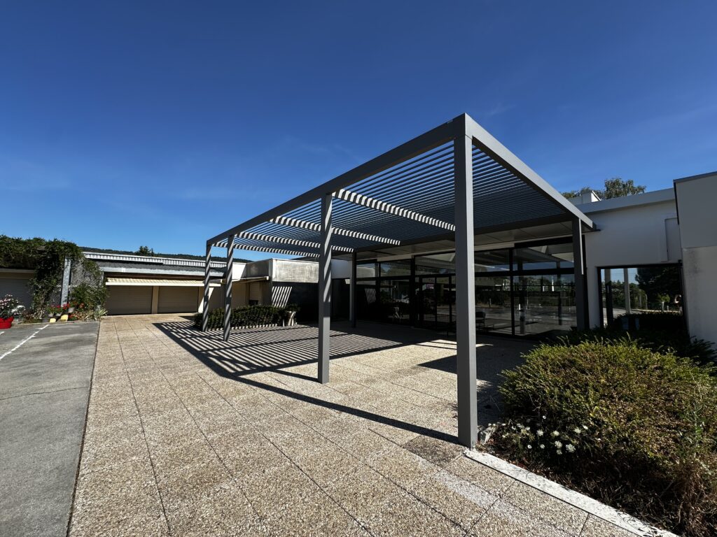 Pergola en aluminium sur mesure installée devant un bâtiment professionnel à Quingey.