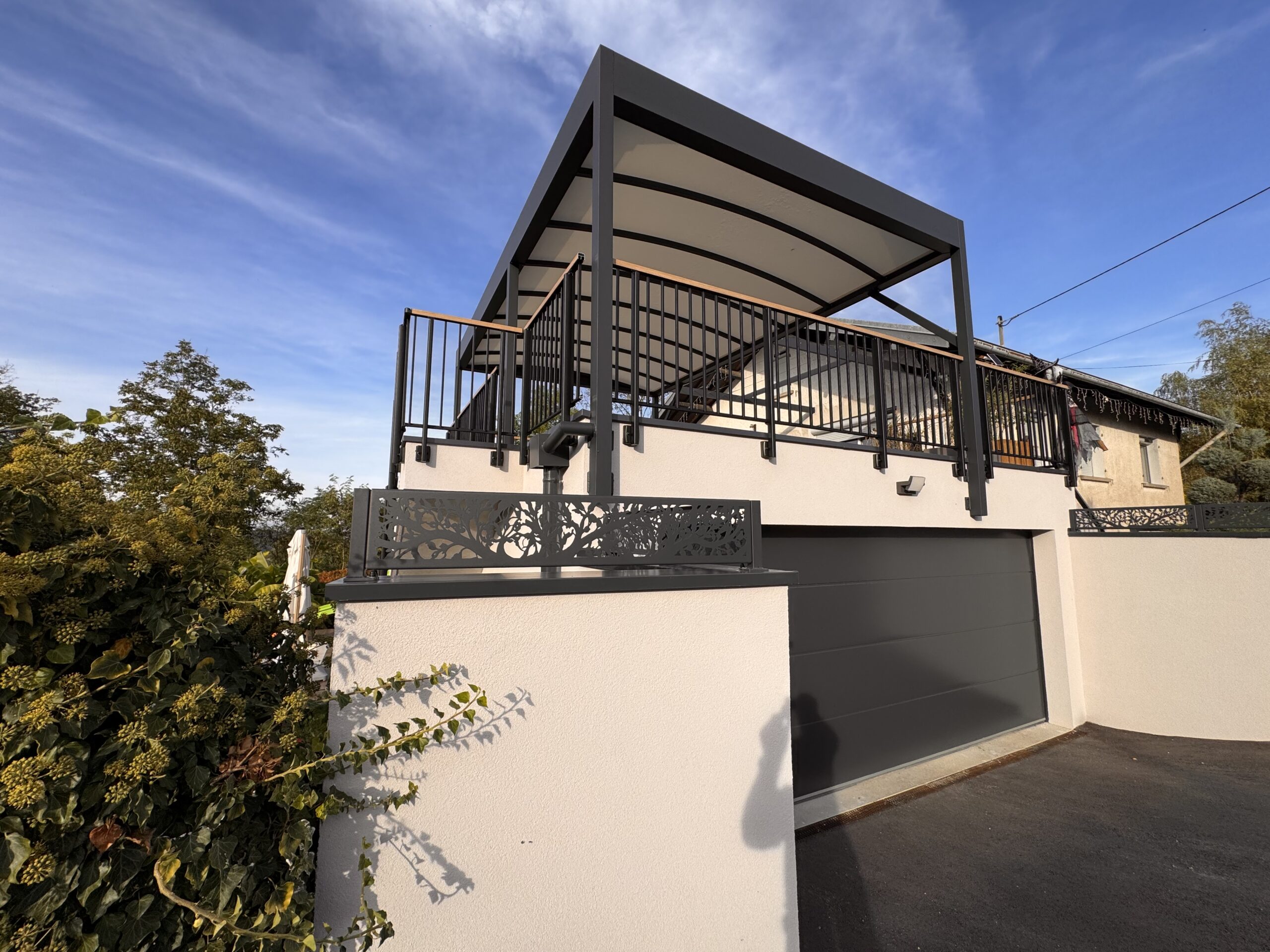Pergola à toile avec structure gris anthracite installée au-dessus d'une terrasse surélevée avec garde-corps métalliques.
